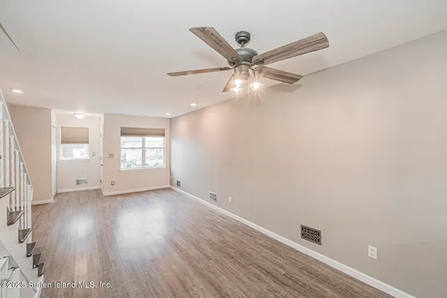 an empty room with wooden floor fan and windows