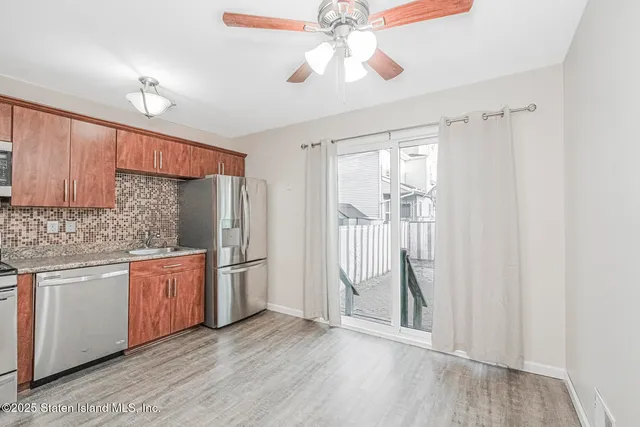 a kitchen with stainless steel appliances granite countertop a refrigerator a sink dishwasher a stove and white cabinets with wooden floor