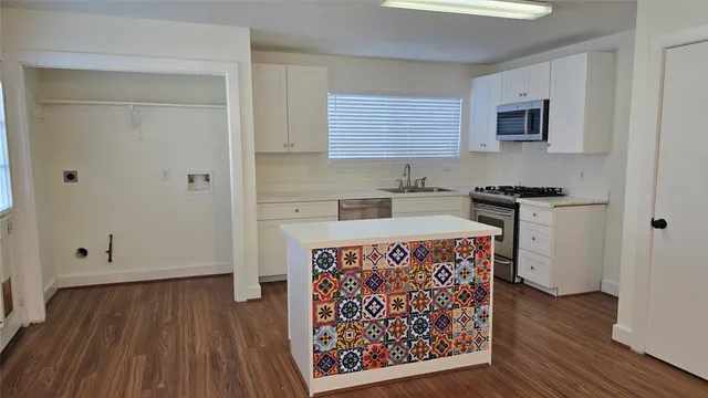 a kitchen with stainless steel appliances granite countertop a stove a refrigerator a sink a microwave oven with wooden floor and cabinets