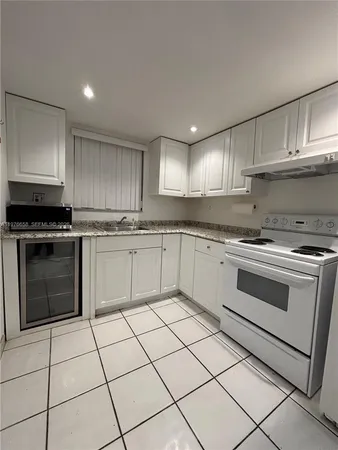 a white kitchen with granite countertop stainless steel appliances a stove sink and cabinets