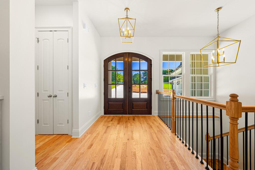 707 Vickery Street Extension Hartwell, GA 30643 - Photo 4 of 50 Enter into a welcoming foyer showcasing rich hardwood flooring and a classic wood banister, illuminated by modern fixtures.