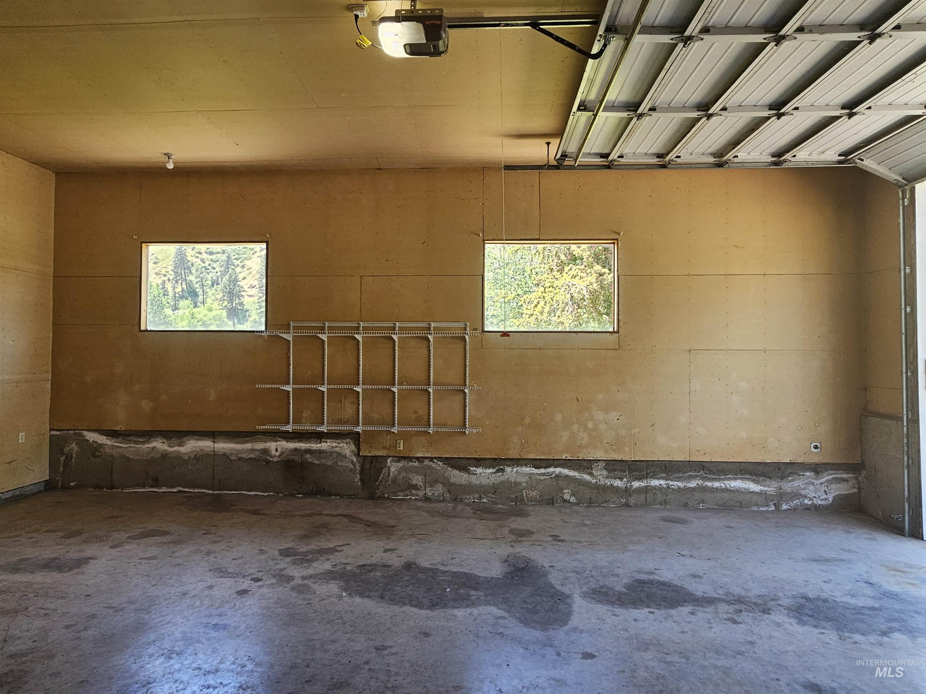 29865 Mission Creek Road Culdesac, ID 83524 - Photo 36 of 43 Spacious garage with concrete floor, two windows, built-in shelving, and an overhead garage door opener