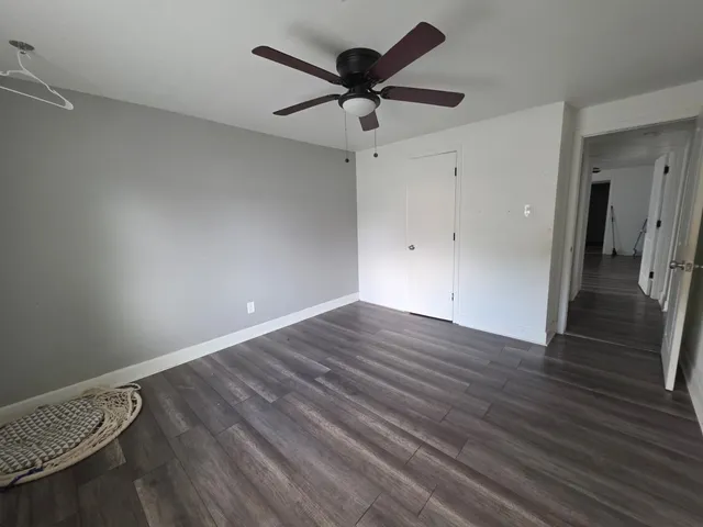 an empty room with wooden floor and a ceiling fan