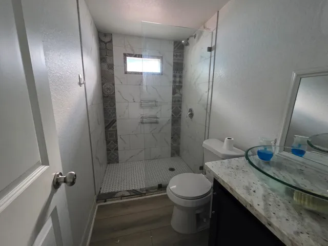 a bathroom with a granite countertop sink toilet and shower