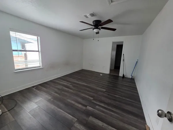 a view of empty room with wooden floor and fan