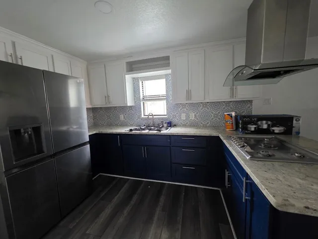 a kitchen with granite countertop stainless steel appliances a refrigerator a sink and wooden cabinets