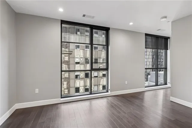 a kitchen with stainless steel appliances granite countertop a refrigerator a sink dishwasher a stove and white cabinets with wooden floor