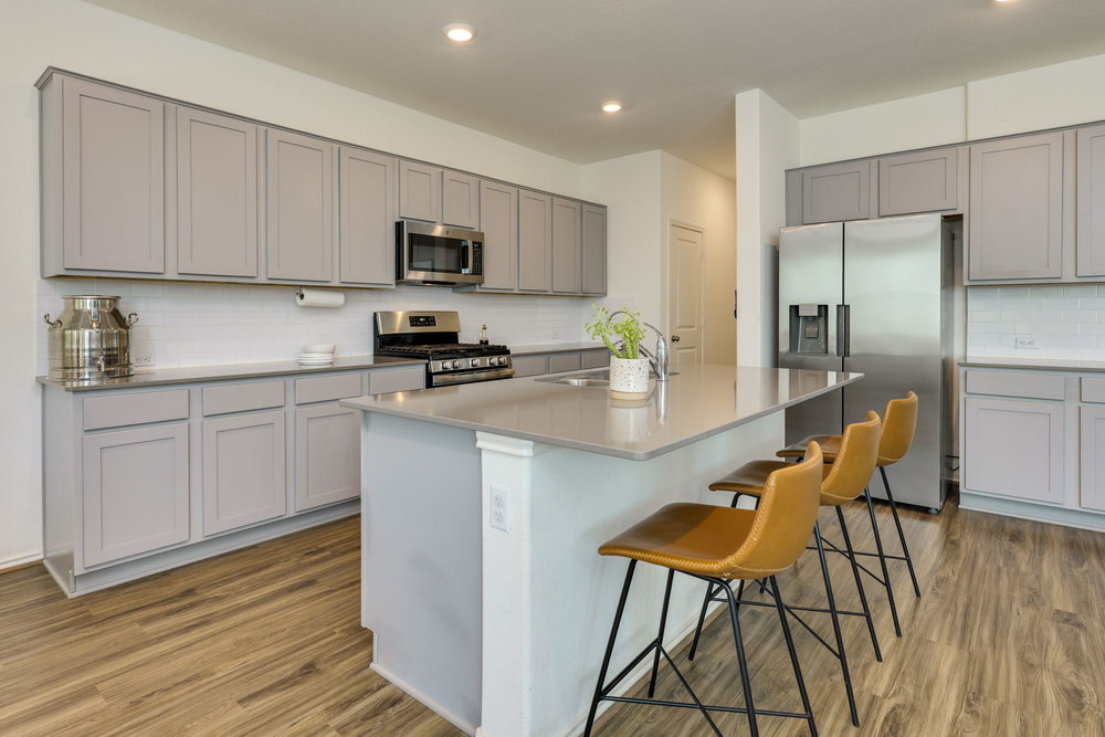 1107 Winifred Drive Austin, TX 78748 - Photo 10 of 40 A sleek kitchen with soft gray cabinetry, gas cooking, and generous prep space.