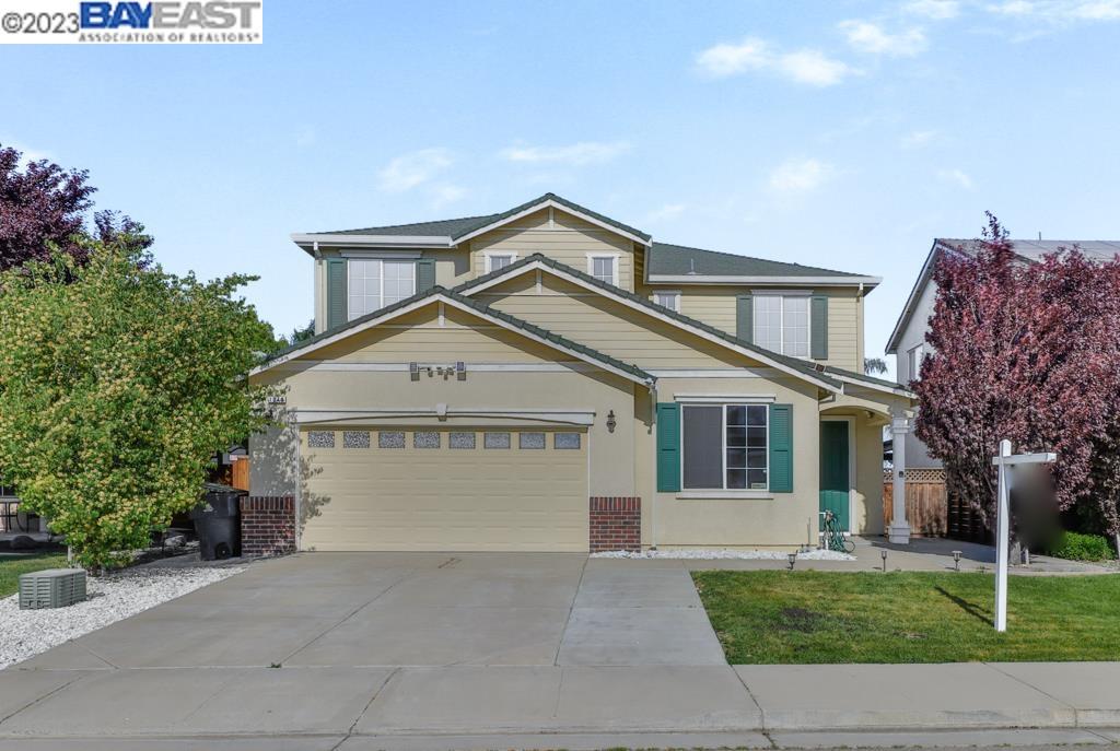 a view of a house with a yard plants and large tree