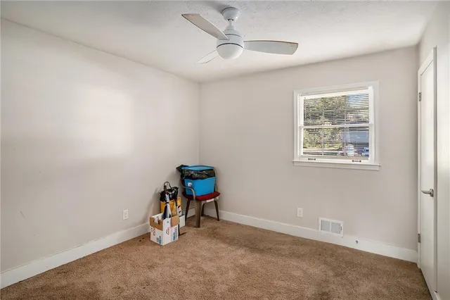 an empty room with windows and ceiling fan