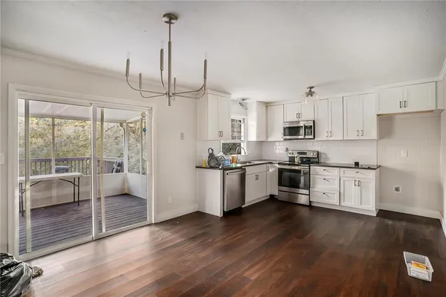 a kitchen with stainless steel appliances granite countertop a refrigerator a sink and white cabinets with wooden floor