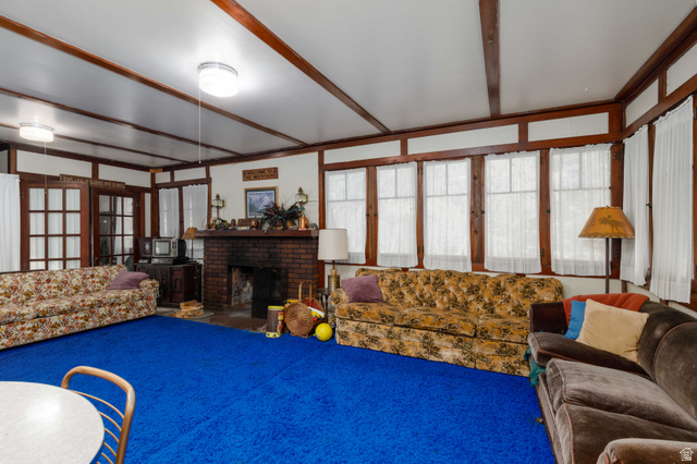 6449 North North Fork Road Eden, UT 84310 - Photo 10 of 38 Spacious interior room featuring a prominent brick fireplace with a mantel, multiple windows, double French doors, and exposed ceiling beams