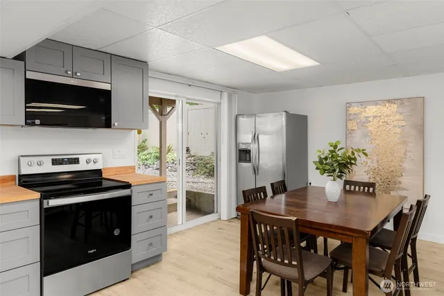 a kitchen with stainless steel appliances a stove a sink dishwasher a refrigerator with a dining table and chairs