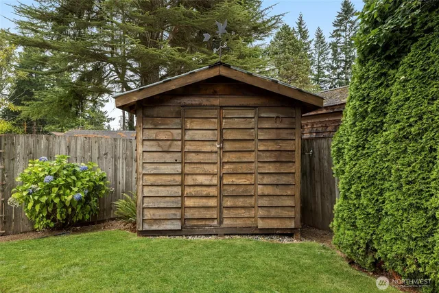 a view of a house with a yard plants and large tree