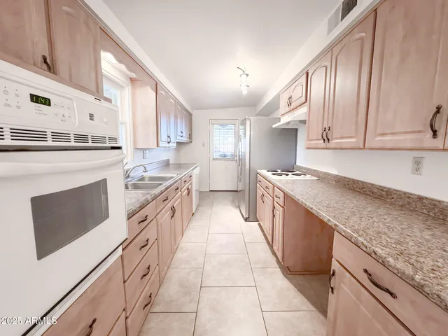 a large kitchen with stainless steel appliances granite countertop a stove a sink and a refrigerator