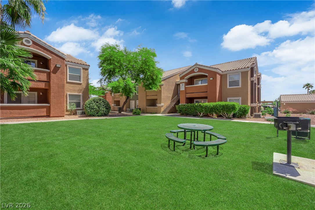 8101 West Flamingo Road, Unit 2030 Las Vegas, NV 89147 - Photo 4 of 27 A well-maintained lawn with a picnic area and barbecue facilities sits between modern multi-story buildings.
