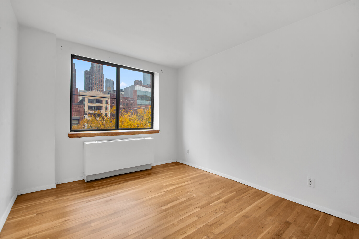 414 West 54th Street, Unit 5B Manhattan, NY 10019 - Photo 8 of 12 a view of an empty room with wooden floor and a window