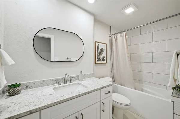 a bathroom with a granite countertop toilet a sink and a mirror