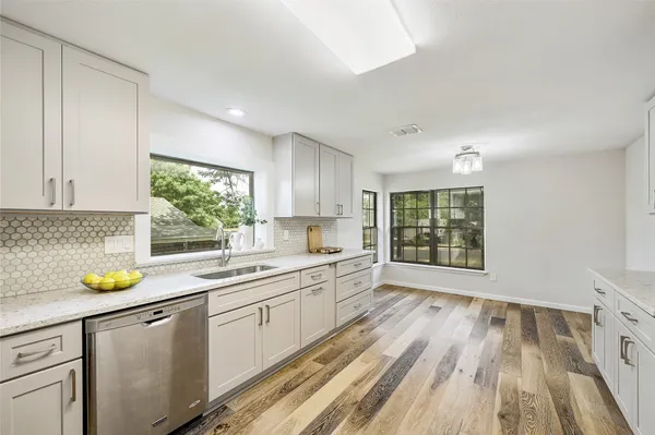 a kitchen with a sink a window appliances and cabinets