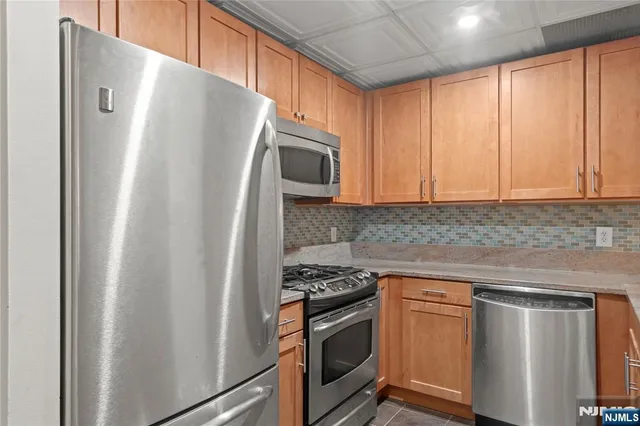 a kitchen with stainless steel appliances granite countertop a refrigerator sink and stove