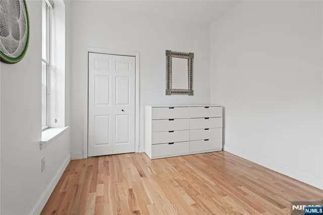 a view of a bedroom with wooden floor and dresser