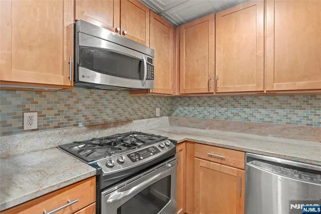 a kitchen with granite countertop a stove top oven cabinetry a sink and a window