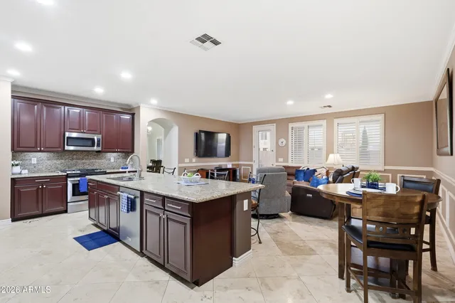 a large kitchen with a large counter top space a sink stainless steel appliances and cabinets