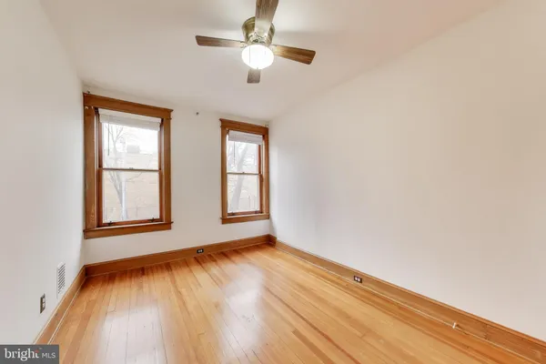 a view of an empty room with wooden floor and windows
