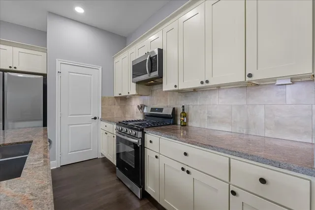 a kitchen with stainless steel appliances granite countertop white cabinets and a granite counter tops