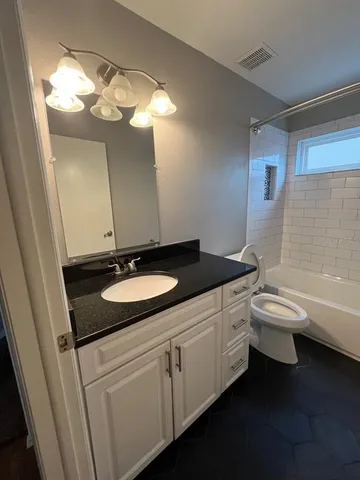a bathroom with a granite countertop sink toilet and bathtub