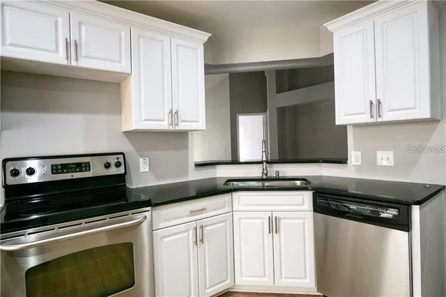 a kitchen with cabinets stainless steel appliances and wooden floor