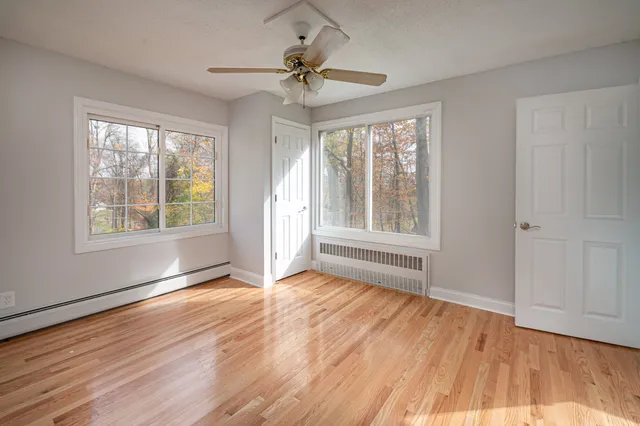 a view of an empty room with a window and wooden floor