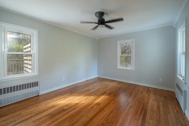 a view of empty room with wooden floor and fan