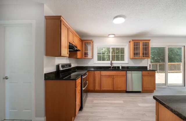 a kitchen with granite countertop a stove a sink and a microwave
