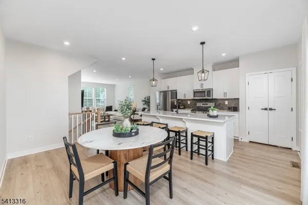 a kitchen with a dining table chairs wooden floor cabinets and appliances