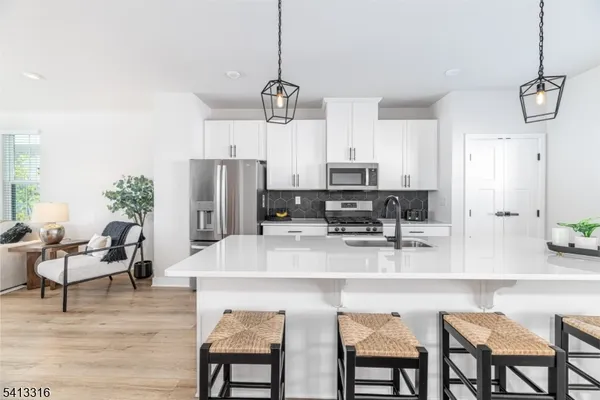 a kitchen with stainless steel appliances kitchen island granite countertop a table chairs and a refrigerator