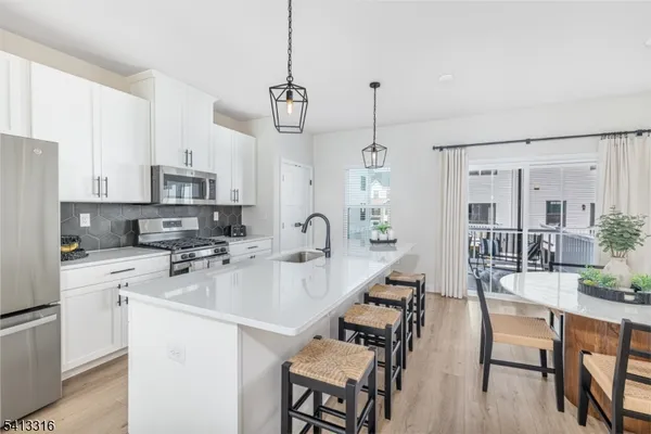 a open kitchen with stainless steel appliances granite countertop a stove a refrigerator a kitchen island a sink dishwasher a dining table and chairs with wooden floor
