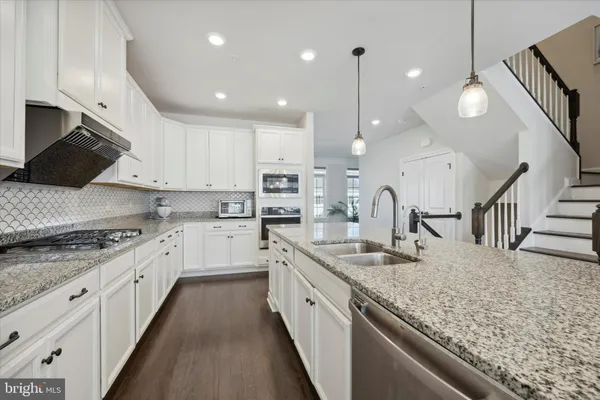 a large kitchen with granite countertop a sink a counter top space stainless steel appliances and cabinets