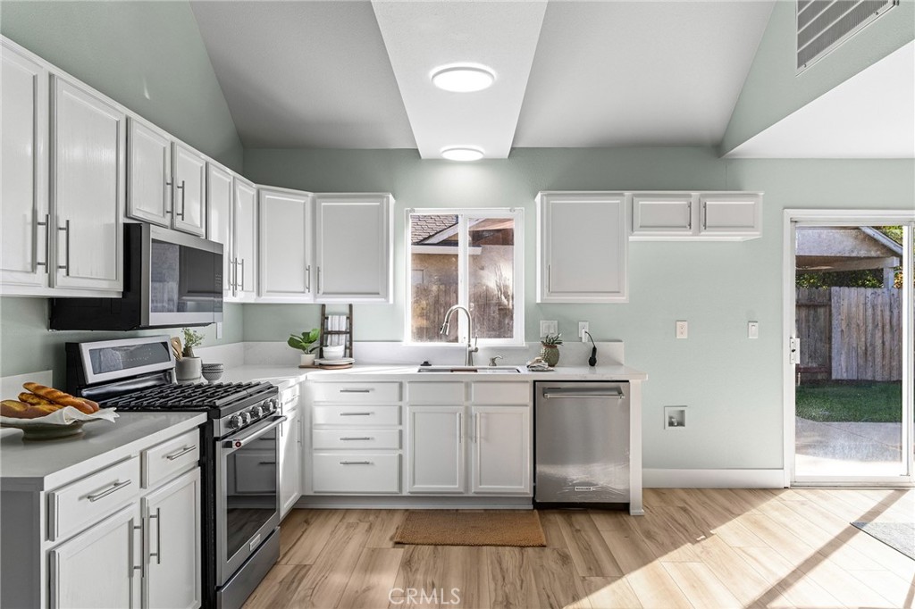 1572 Arch Way Chico, CA 95973 - Photo 9 of 43 a kitchen with stainless steel appliances a sink dishwasher a stove top oven a refrigerator with white cabinets and wooden floor