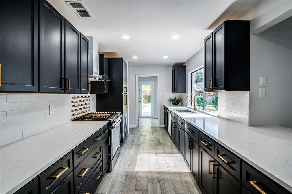 6000 Blue Ridge Trail Plano, TX 75023 - Photo 10 of 25 Kitchen featuring light stone countertops, tasteful backsplash, stainless steel gas range oven, dark cabinets, and light wood-style floors
