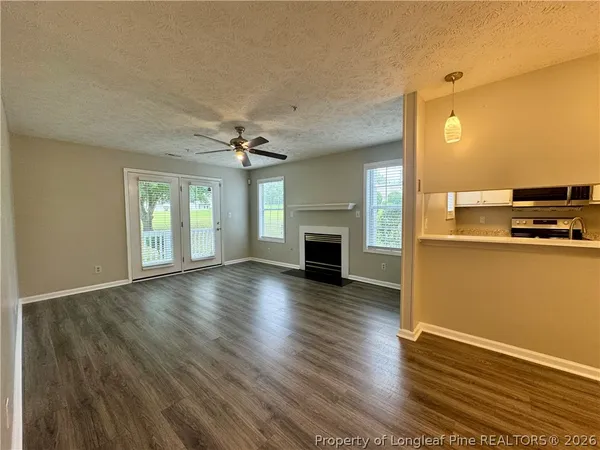 an empty room with wooden floor a fireplace and windows