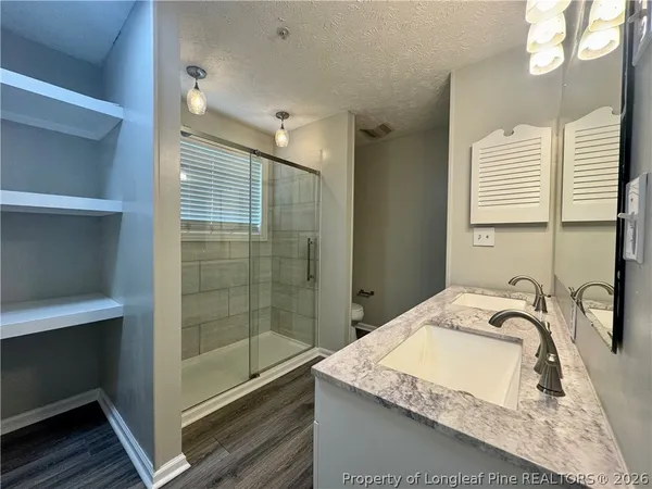 a bathroom with a granite countertop sink a toilet and shower