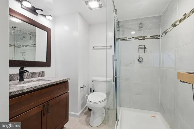 a bathroom with a granite countertop sink toilet and shower