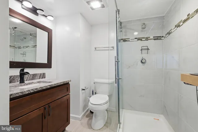 a bathroom with a granite countertop sink toilet and shower