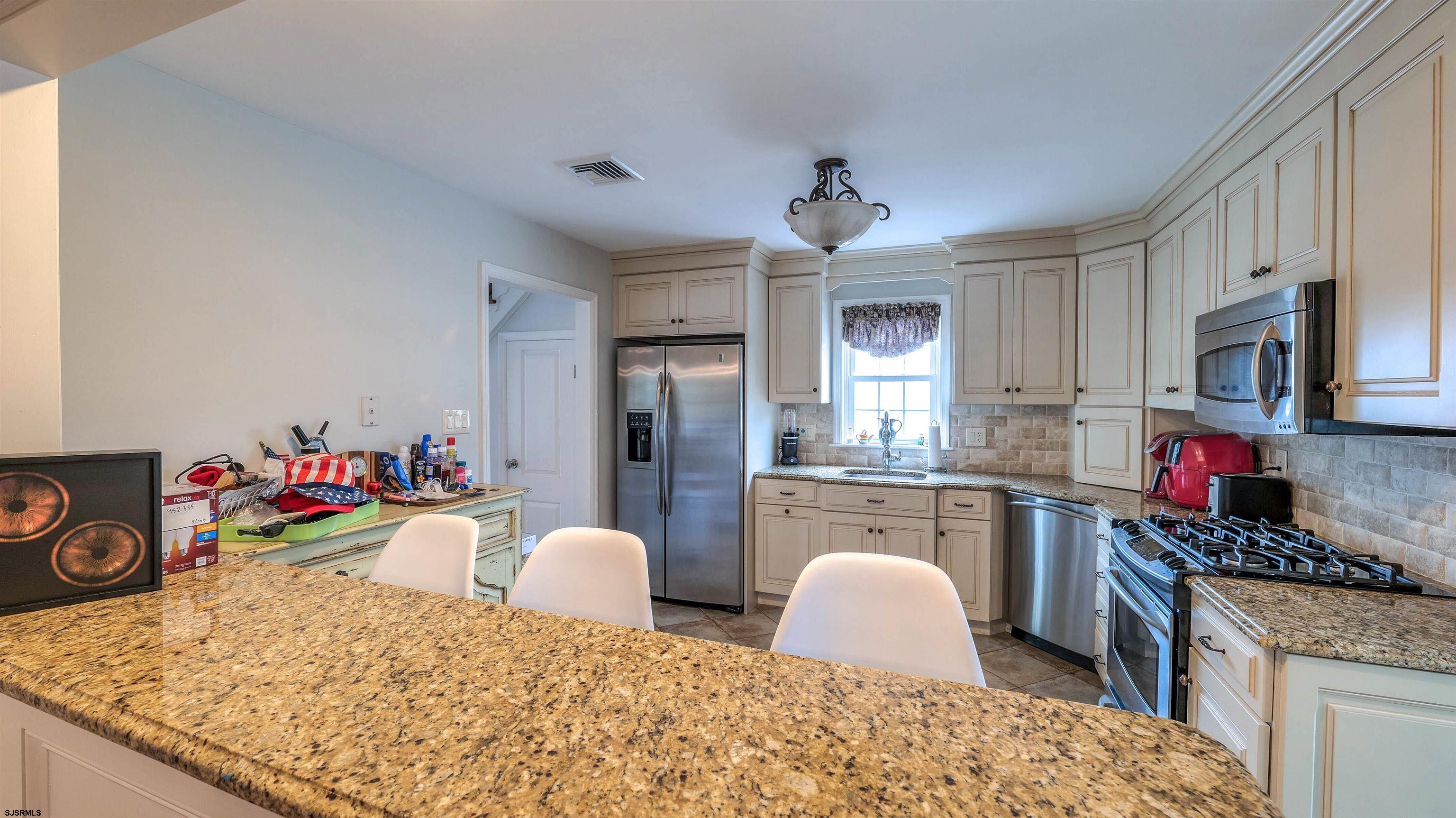 6 North Lancaster Avenue Margate City, NJ 08402 - Photo 13 of 32 a kitchen with stainless steel appliances granite countertop a stove top oven a sink dishwasher and cabinets with wooden floor