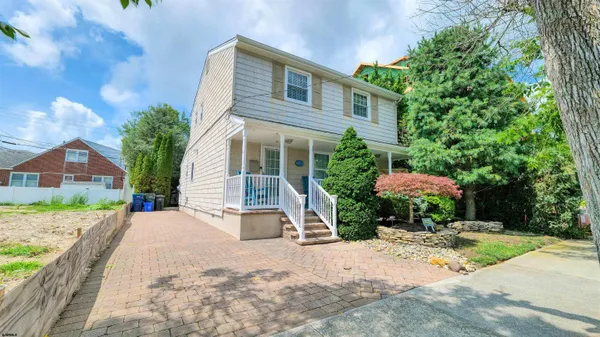 a front view of a house with a yard and potted plants