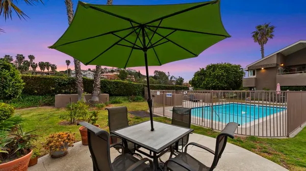 a view of a swimming pool with a table and chairs under an umbrella
