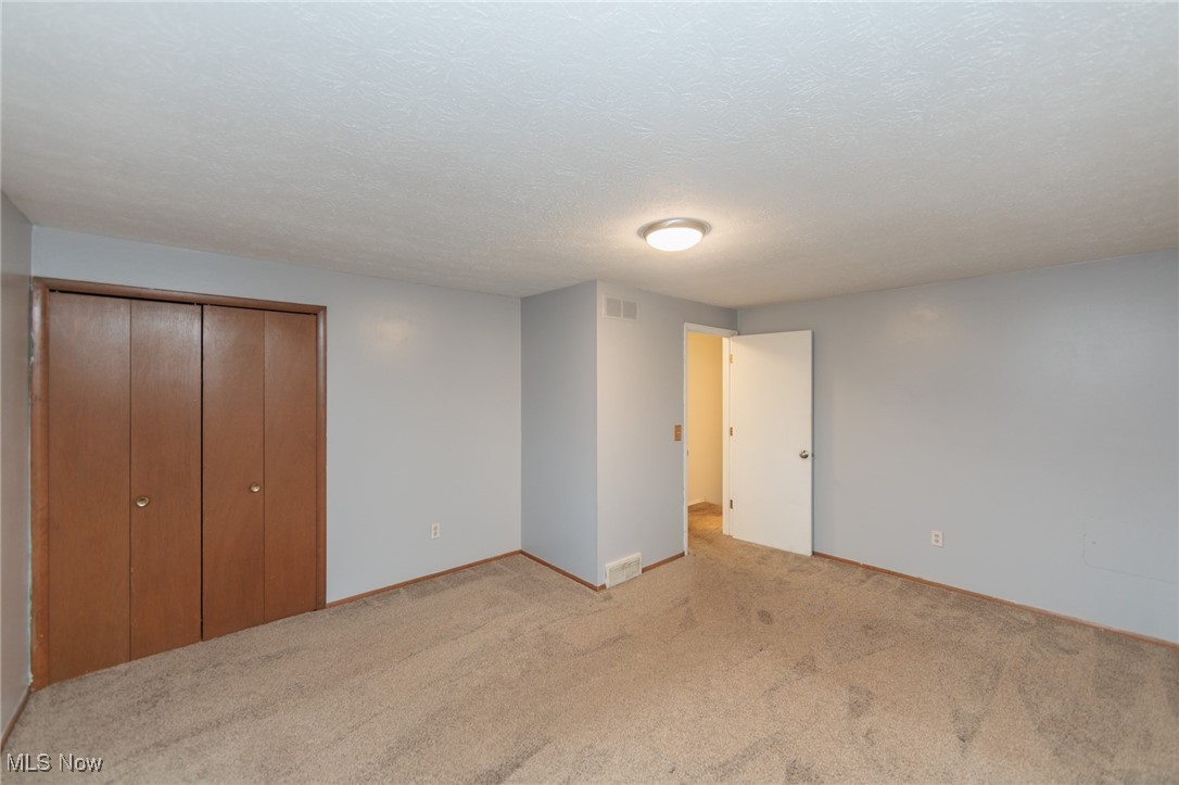 28013 Knickerbocker Road Bay Village, OH 44140 - Photo 21 of 38 Second floor bedroom featuring a textured ceiling, a closet, and light carpet