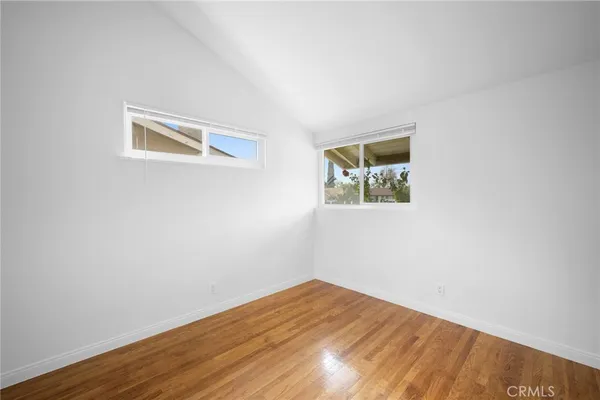 a view of a big room with wooden floor and windows