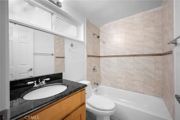 a bathroom with a granite countertop sink mirror toilet and bathtub